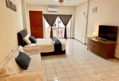 Habitación con 2 camas, TV y sofá. en Bukit Tinggi 1 Hati guesthouse en Bukit Tinggi