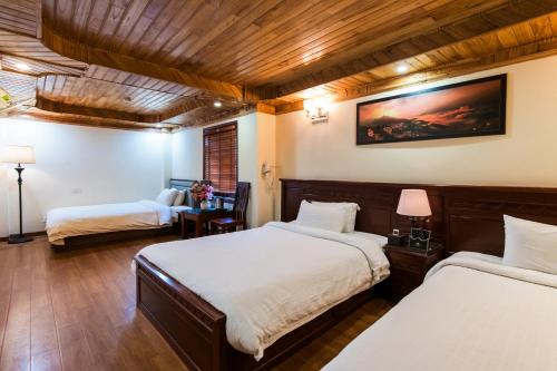 a room with two beds and a chair in it at May Ho Hotel Sapa in Sa Pa