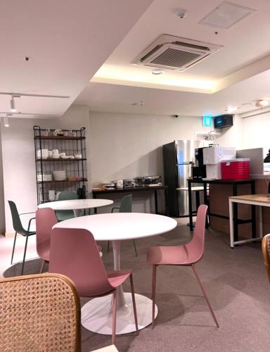 a room with tables and chairs and a kitchen at Geoje Mongdol Beach H Avenue Hotel in Geoje 