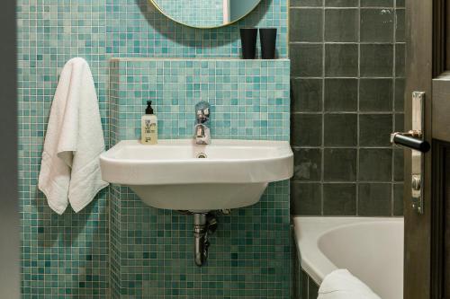 a blue tiled bathroom with a sink and a tub at Brilliant Apartments in Berlin