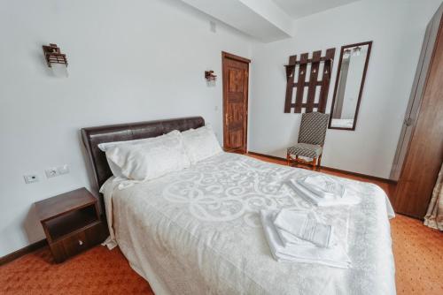 a bedroom with a bed with white sheets and a chair at Complex Turistic Constantin Bucovina in Câmpulung Moldovenesc
