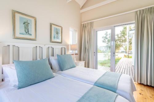 a bedroom with a large white bed with blue pillows at Peaceful Parkland Home on Thesen Islands in Knysna