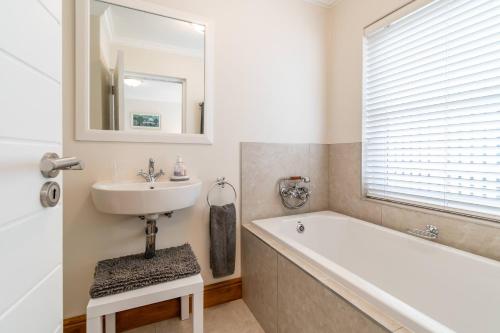 a bathroom with a sink and a tub and a mirror at Peaceful Parkland Home on Thesen Islands in Knysna