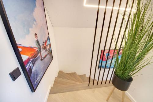 a staircase with a painting and a potted plant at Jūra ir TU in Palanga
