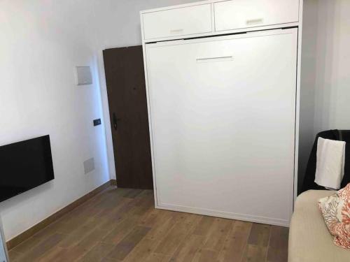 Habitación con armario blanco, sofá y TV. en Casa vistas inmejorables en Carraspite