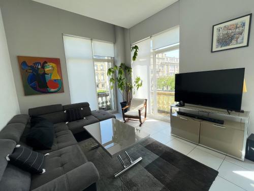 a living room with a couch and a flat screen tv at Vivez en appartement en centre-ville - Hotel de ville - 1 ch in Le Havre