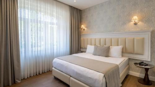 a bedroom with a bed and a large window at Hotel Passport Tbilisi in Tbilisi City