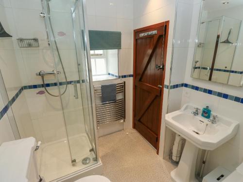 a bathroom with a shower and a toilet and a sink at Candlelight Cottage in Buxton