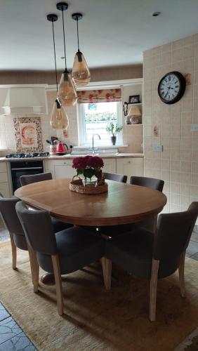 una cucina con tavolo e sedie in legno e orologio di Knockrobin Cottage a Wicklow