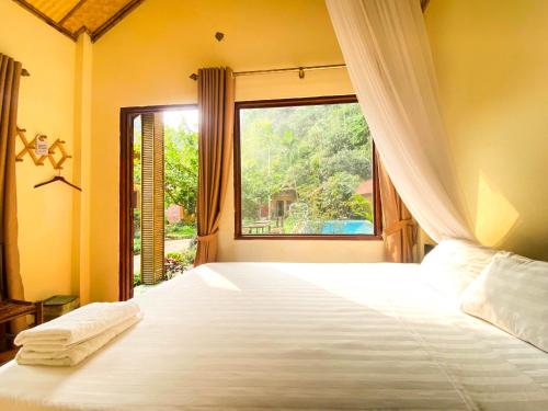 a bedroom with a large bed with a window at Tam Coc Rocky Bungalow in Ninh Binh