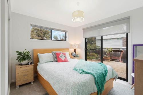 - une chambre avec un lit et une grande fenêtre dans l'établissement Plan Beach, à Merimbula