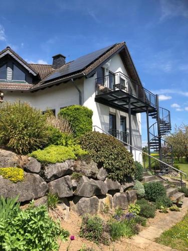 a house with a balcony on top of a rock wall at Ferienwohnung auf dem Maifeld in Gappenach