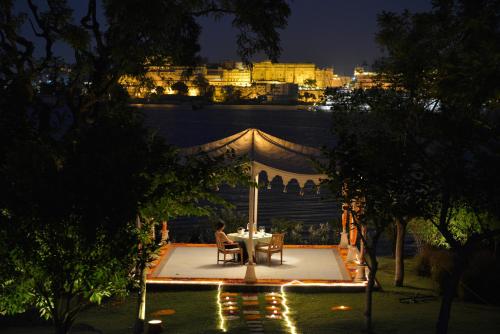 a table and chairs under a tent at night at The Oberoi Udaivilas Udaipur in Udaipur