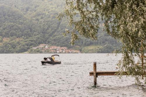 a boat in a lake with a person in it at Villa Antica Colonia SPA & Wellness in Pettenasco