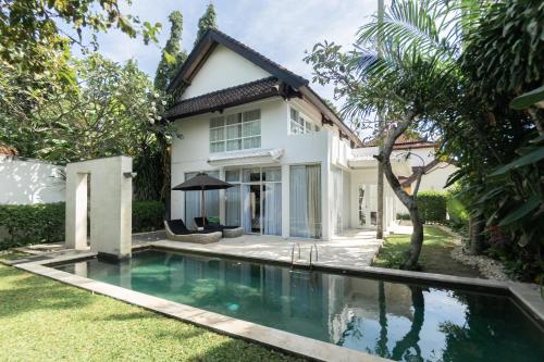 a swimming pool in front of a house at Shanti Retreat in Seminyak