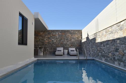 a swimming pool with two chairs and a house at Paligremnos Infinity in Plakias