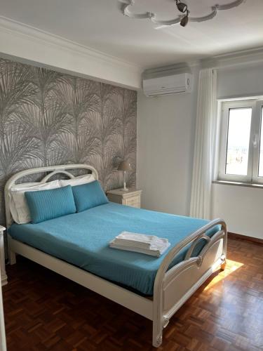 um quarto com uma cama com lençóis azuis e uma parede em Flipflops Apartments 1 na Nazaré