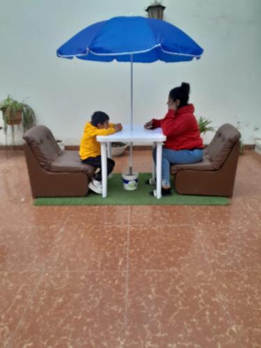 due persone sedute intorno a un tavolo con un ombrello di HOTEL CHORRILLOS BEACH a Barranca