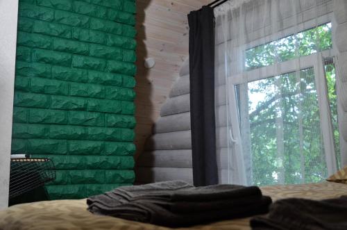 a bedroom with a green brick wall and a window at Hotel resort Sedula in Skogalis