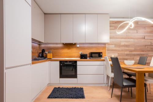 a kitchen with white cabinets and a wooden table at Urban Elegance at Its Finest Stylish 1-BD Flat in Sofia