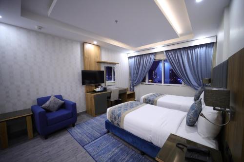 a hotel room with a bed and a blue chair at PRIMOTEL Elite As Salamah - Serviced Apartments in Jeddah