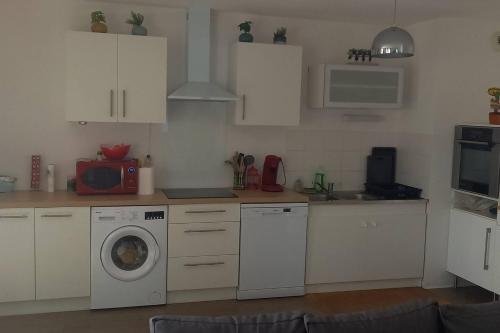a kitchen with white cabinets and a washing machine at Beau appartement T3 in Montpellier