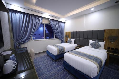 a hotel room with two beds and a window at PRIMOTEL Elite As Salamah - Serviced Apartments in Jeddah