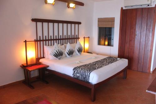 a bedroom with a large bed with two lamps on it at The Long Beach Resort & Spa in Koggala