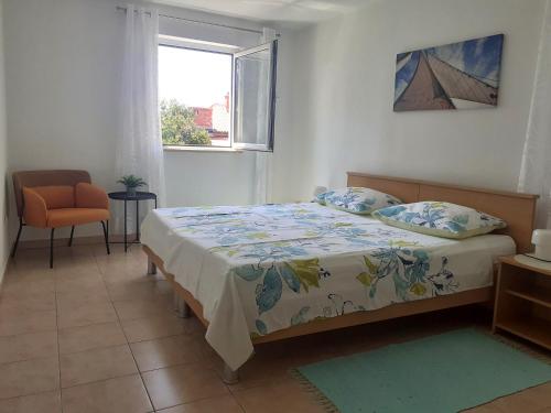a bedroom with a bed and a window and a chair at Apartments Zlata In the Heart of the Old Town, Close to the Beach in Rab