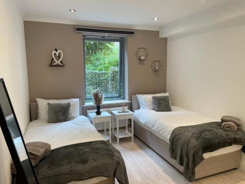two beds in a room with a window at Perfect Stay for Families & Business in CR2 - with FREE parking & 10mins from East Croydon in Purley