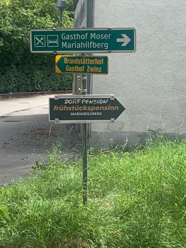 a street sign with several signs in the grass at Dorfpension Mariahilfberg in Gutenstein