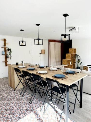 - une grande table en bois avec des chaises dans l'établissement Convivial appartement de charme avec balcon , 95 m2 en hyper-centre de Saint-Brieuc. Tout confort, grand salon avec vidéoprojecteur - 3 chambres - Parking, à Saint-Brieuc