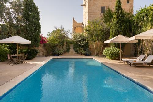 a swimming pool with two chairs and umbrellas at CASA SAN ROCCO - Luxurious Grand 18th C. Palace with Gardens & Pool in Hal Ghaxiak