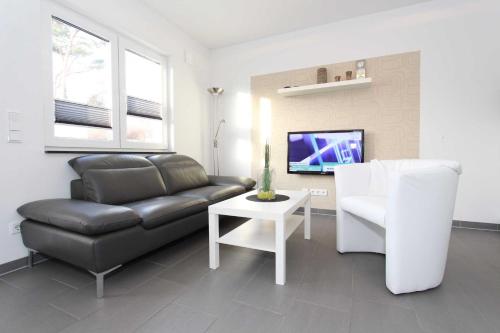 uma sala de estar com um sofá de couro e uma televisão em Bungalow Mariannenweg 4 em Tarnewitz