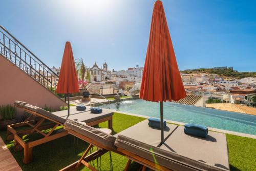 阿爾布費拉的住宿－Vila Origens Boutique Hotel Albufeira – Adults Only，建筑物屋顶上两张桌子和雨伞