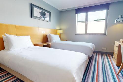 um quarto de hotel com duas camas e uma janela em Village Hotel Swansea em Swansea
