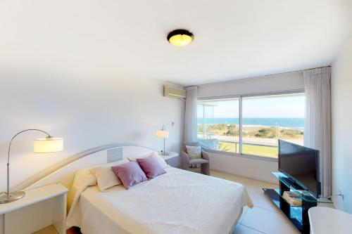 a bedroom with a bed and a window with the ocean at Oceana Suites en Esturion, frente a playa Brava in Punta del Este