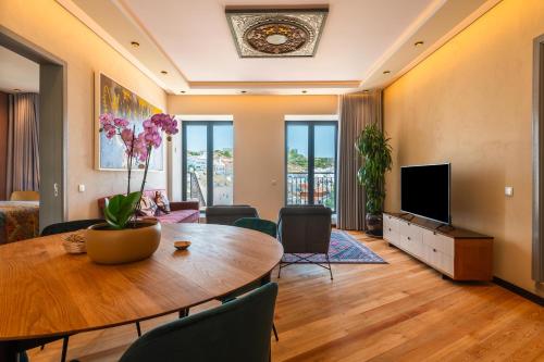 a living room with a table and a tv at Vila Origens Boutique Hotel Albufeira – Adults Only in Albufeira