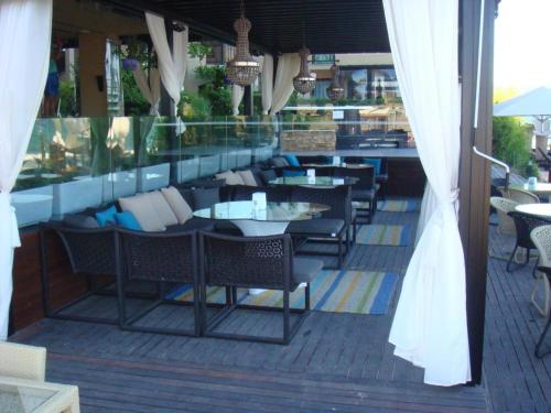 ein Restaurant mit Tischen und Stühlen auf einer Terrasse in der Unterkunft Апартаменти Оазис Вип клуб in Sonnenstrand