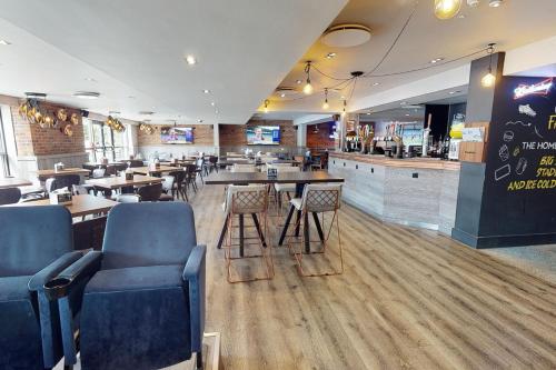a restaurant with tables and chairs and a bar at Village Hotel Swansea in Swansea