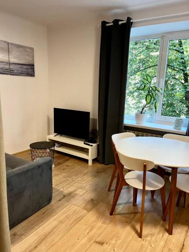 ein Wohnzimmer mit einem Tisch und einem TV in der Unterkunft OhMyHome - Hala Mirowska in Warschau