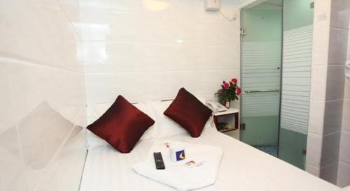 un letto bianco con due cuscini rossi sopra di Relaince Inn a Hong Kong