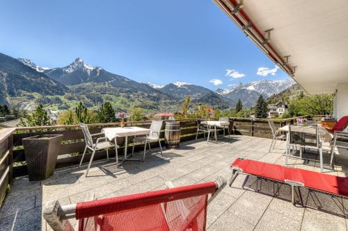 a patio with tables and chairs and mountains in the background at Ferienhaus Tinabella - bei der Hochjochbahn - Sivretta Montafon in Schruns-Tschagguns