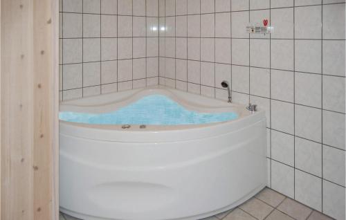 a bath tub in a tiled bathroom at Nice Home In Oksbl With 3 Bedrooms, Sauna And Wifi in Oksbøl