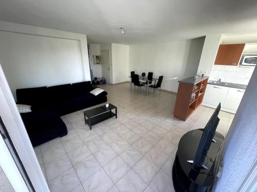 un salon avec un canapé noir et une cuisine dans l'établissement Appartement Vasseur T3 Grande Terrasse, à Toulouse