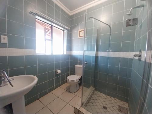 a bathroom with a shower and a toilet and a sink at The Emerald in Pretoria