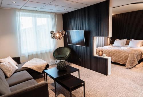 a living room with a bed and a couch and a television at Vann Spa Hotell & Konferens in Brastad