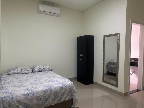 1 dormitorio con cama y espejo en Casa Parque do Bosque - Tangara da Serra en Tangara da Serra
