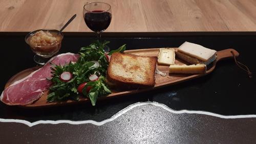 a plate of food with bread and cheese and a glass of wine at les bois de ravel chambres d'hôtes in Ravel
