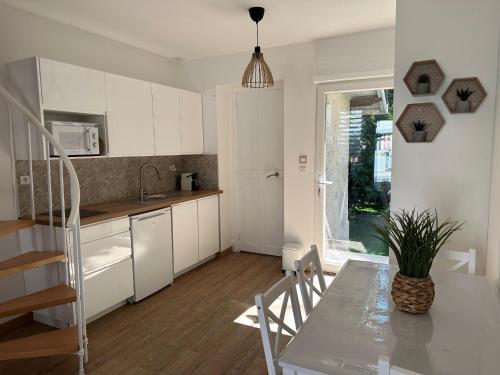 une cuisine avec des armoires blanches et une table avec une plante dans l'établissement Maison de ville avec jardin, à Valence